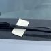 A small rectangular, folded piece of paper pinned under the windshield wiper blade on a silver car, parked and unoccupied.